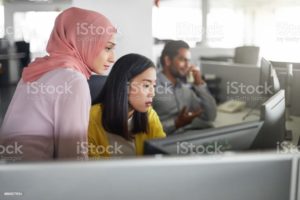 Businesswomen discussing over desktop PC in office.